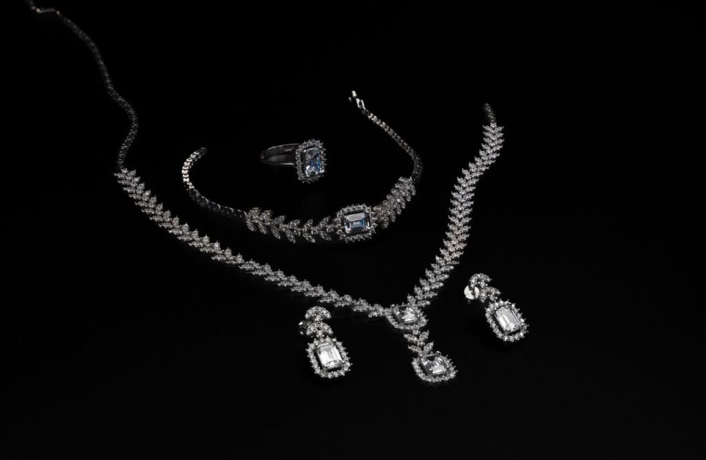 Elegant diamond jewelry set including necklace, bracelet, ring, and earrings on a black backdrop.