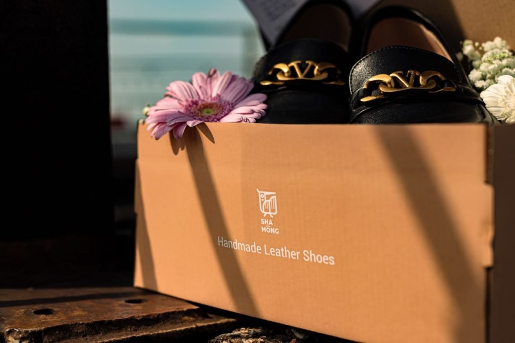 Luxury handmade leather shoes in an elegant gift box with flowers.
